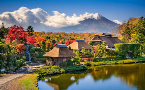 Traditional village with thatched roofs and pond, Mt. Fuji in background, Oshino Hakkai, Japan.