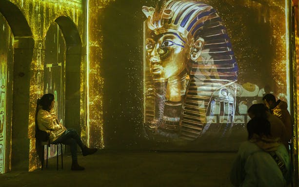 Visitors viewing King Tutankhamun projection at Mysterious Egypt exhibition.