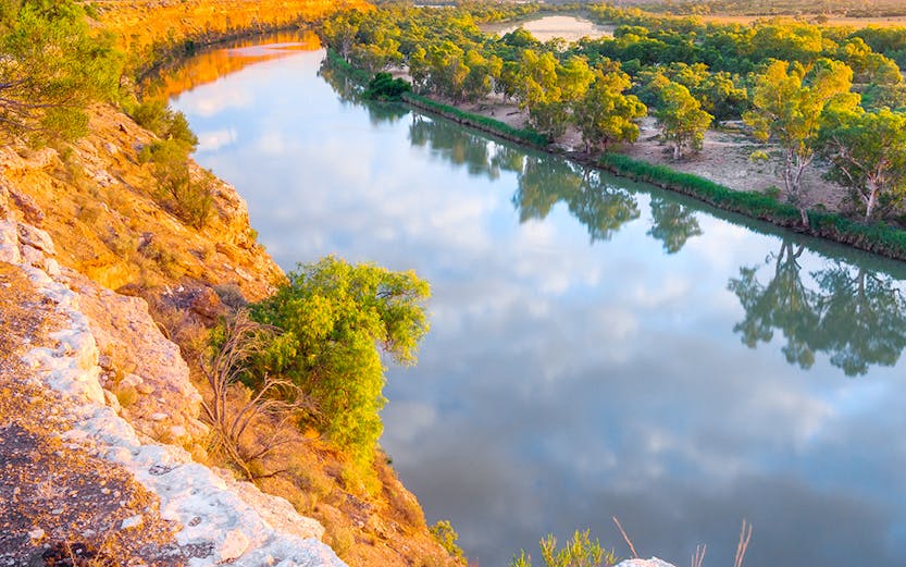 Murray River view with cliffs and trees at sunset, Australia.
