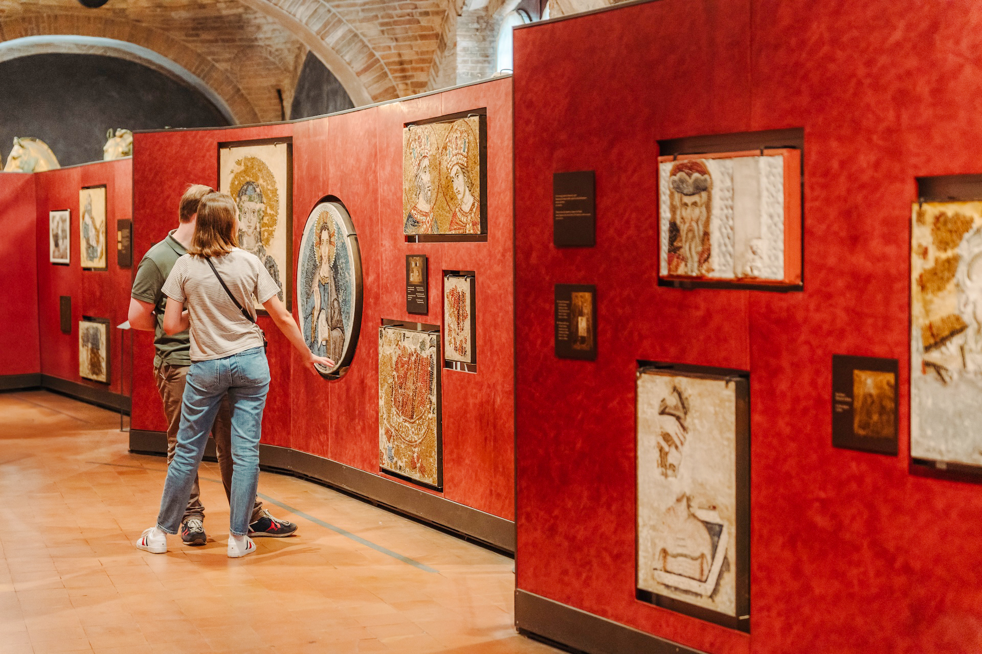 Visitors viewing mosaics at Doge's Palace exhibit during guided tour.