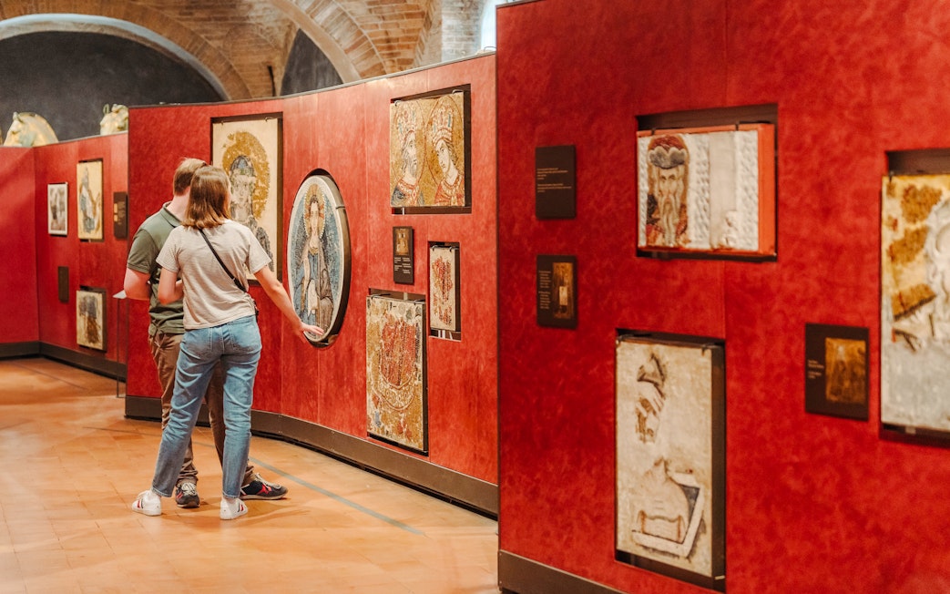 Visitors viewing mosaics at Doge's Palace exhibit during guided tour.