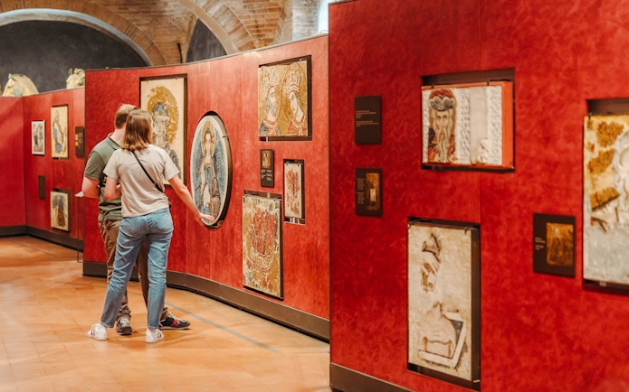 Visitors viewing mosaics at Doge's Palace exhibit during guided tour.