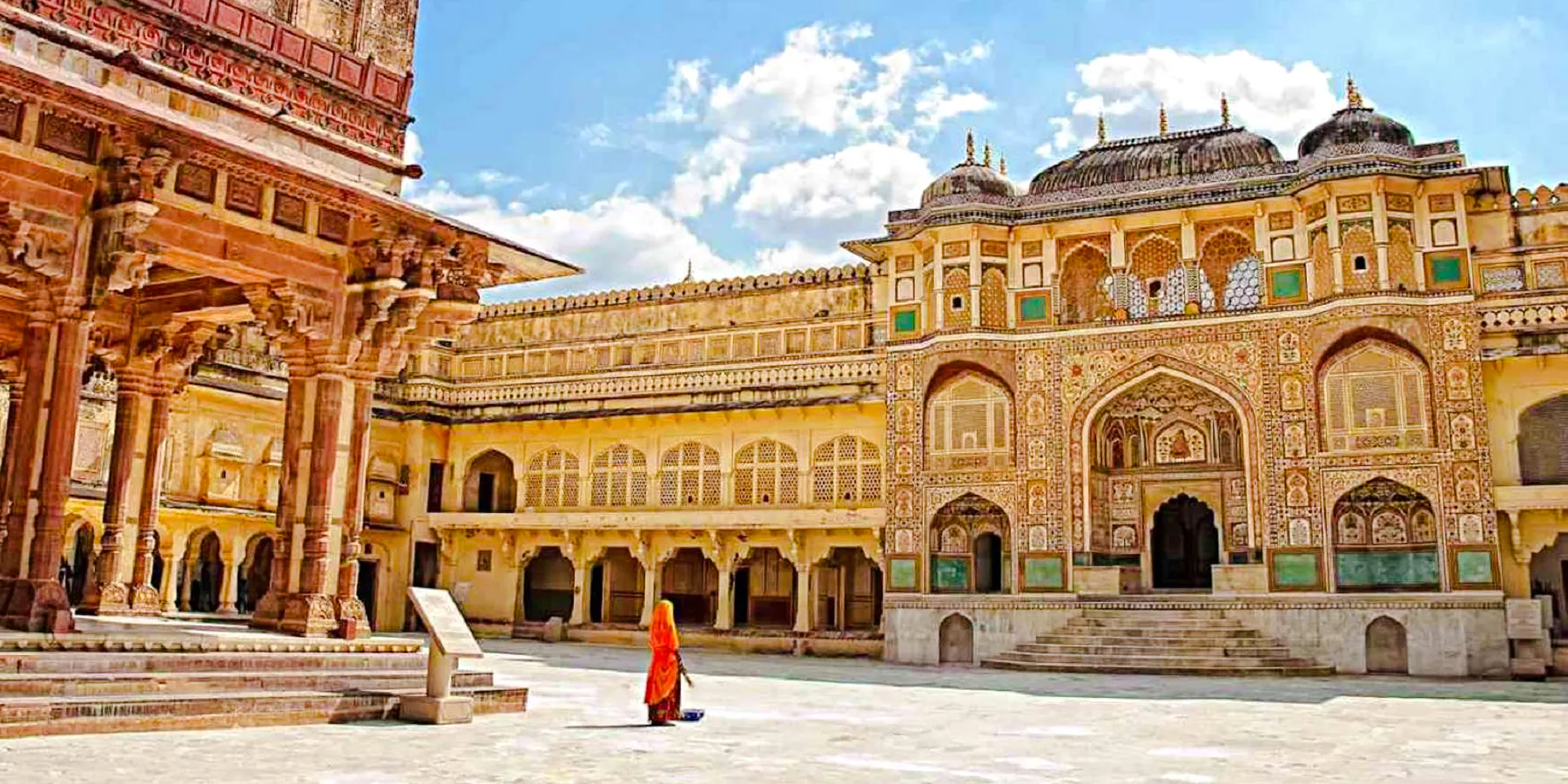Amber Fort courtyard in Jaipur with intricate architecture and a person in traditional attire.