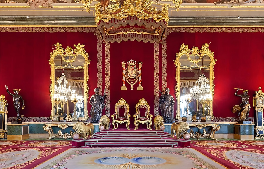 Royal Palace of Madrid throne room with ornate red and gold decor.