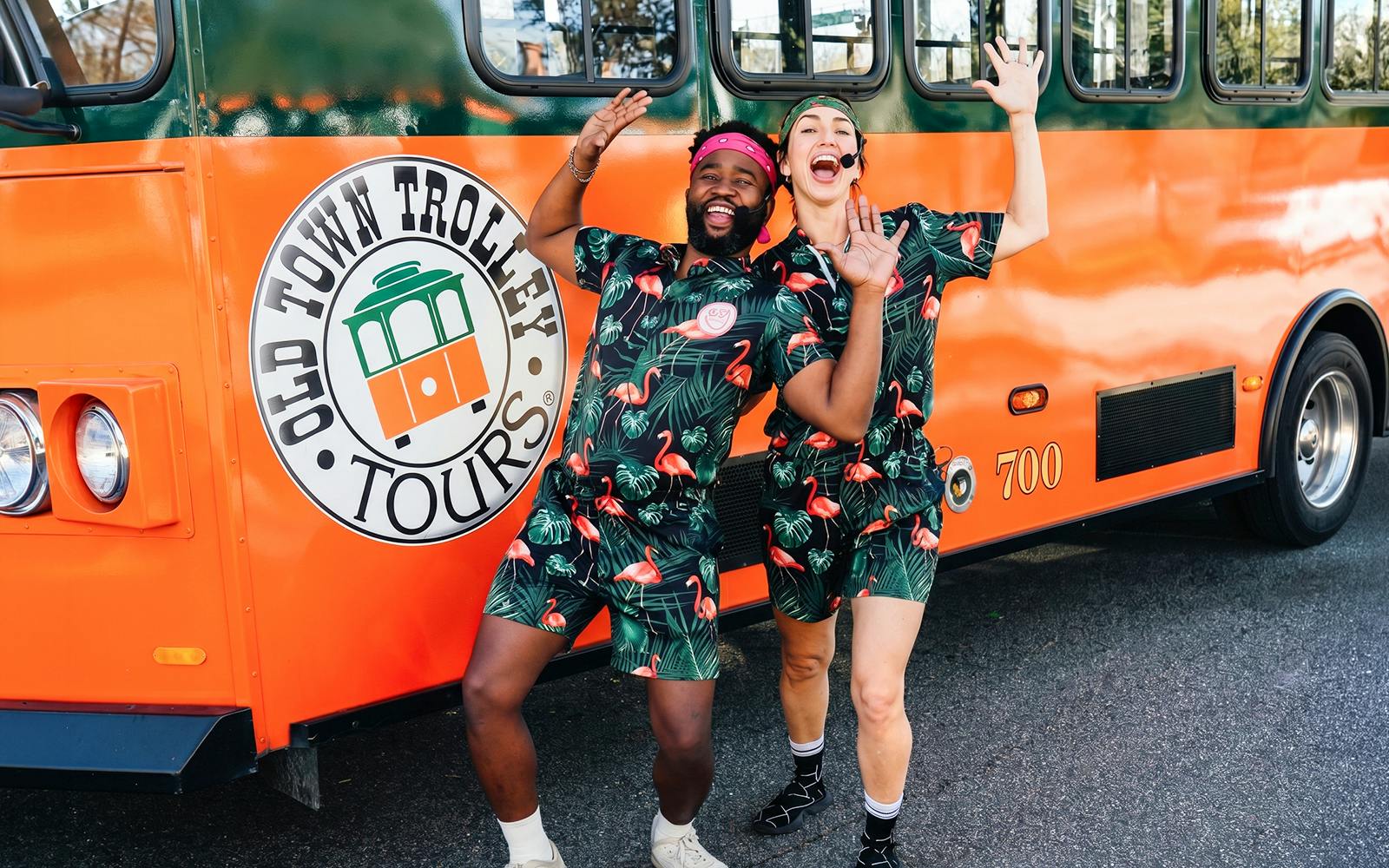 People in matching outfits posing excitedly in front of a Savannah trolley.