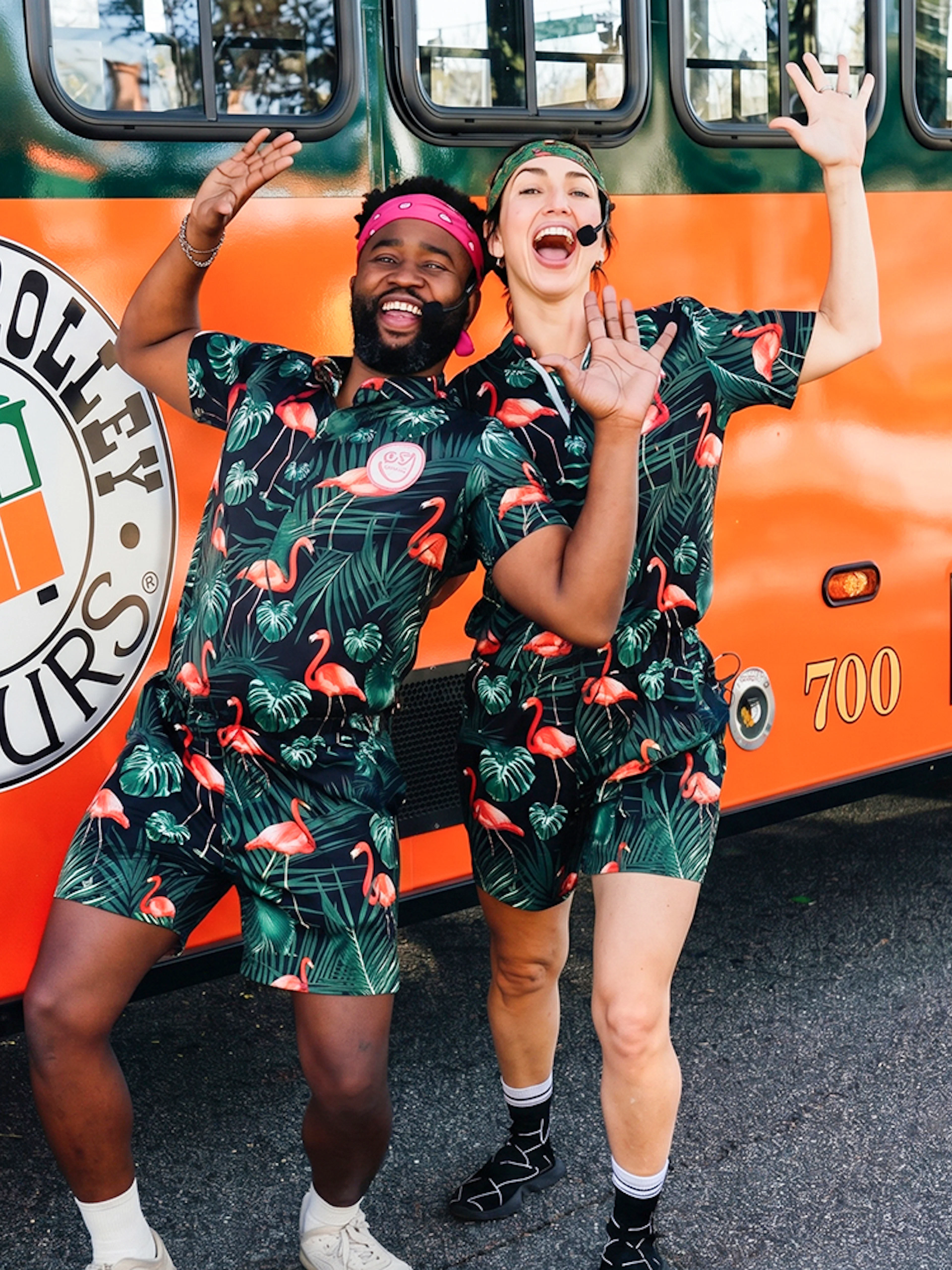 People in matching outfits posing excitedly in front of a Savannah trolley.