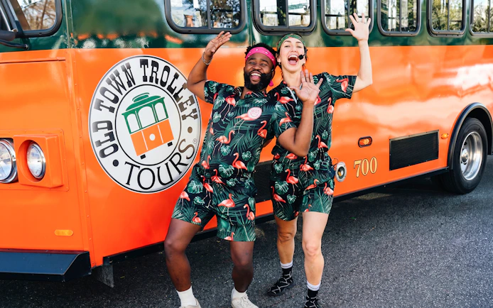 People in matching outfits posing excitedly in front of a Savannah trolley.