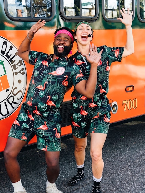 People in matching outfits posing excitedly in front of a Savannah trolley.