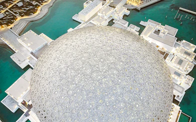 Louvre Museum Abu Dhabi dome with surrounding water and architecture.