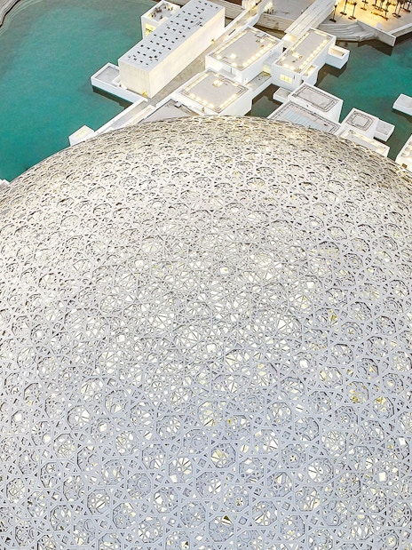 Louvre Museum Abu Dhabi dome with surrounding water and architecture.