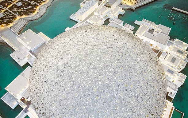 Louvre Museum Abu Dhabi dome with surrounding water and architecture.