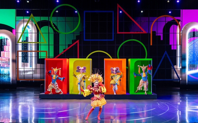 Performers in colorful costumes on stage at a vibrant Colosseum show.