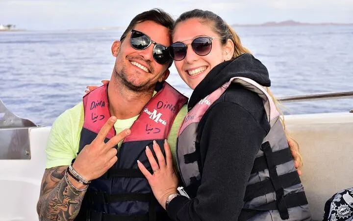 Couple in life jackets on a boat during Red Sea parasailing adventure, Hurghada.