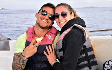 Couple in life jackets on a boat during Red Sea parasailing adventure, Hurghada.