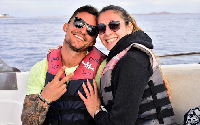 Couple in life jackets on a boat during Red Sea parasailing adventure, Hurghada.