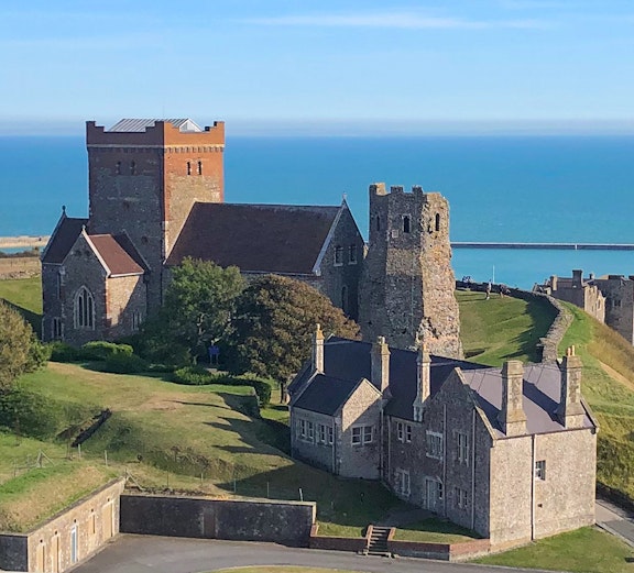 Medieval castle and buildings overlooking the sea on a London to Canterbury tour.