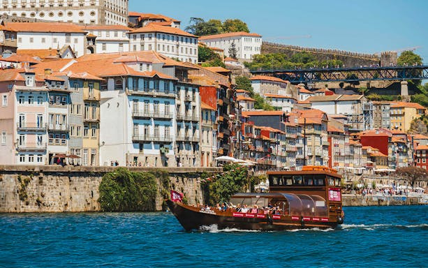 Tourists on a boat ride with a view of Douro River and Porto cityscape.