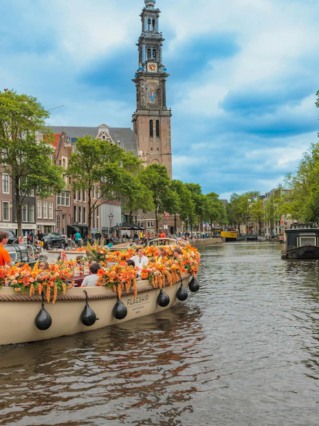 Luxury boat cruising Amsterdam canal with Westerkerk in background.