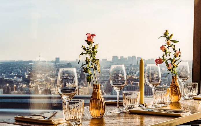 Table set with glasses and flowers overlooking Amsterdam skyline at A'DAM Lookout.