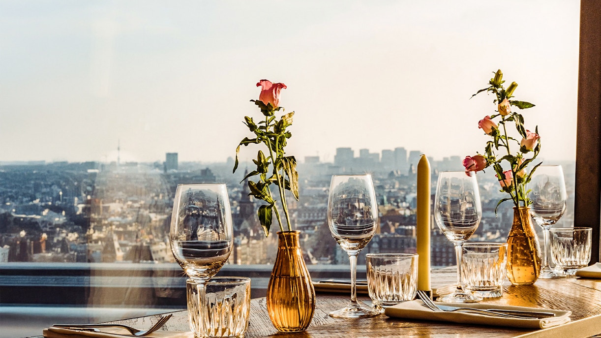 Table set with glasses and flowers overlooking Amsterdam skyline at A'DAM Lookout.