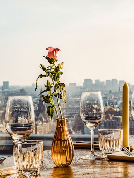 Table set with glasses and flowers overlooking Amsterdam skyline at A'DAM Lookout.