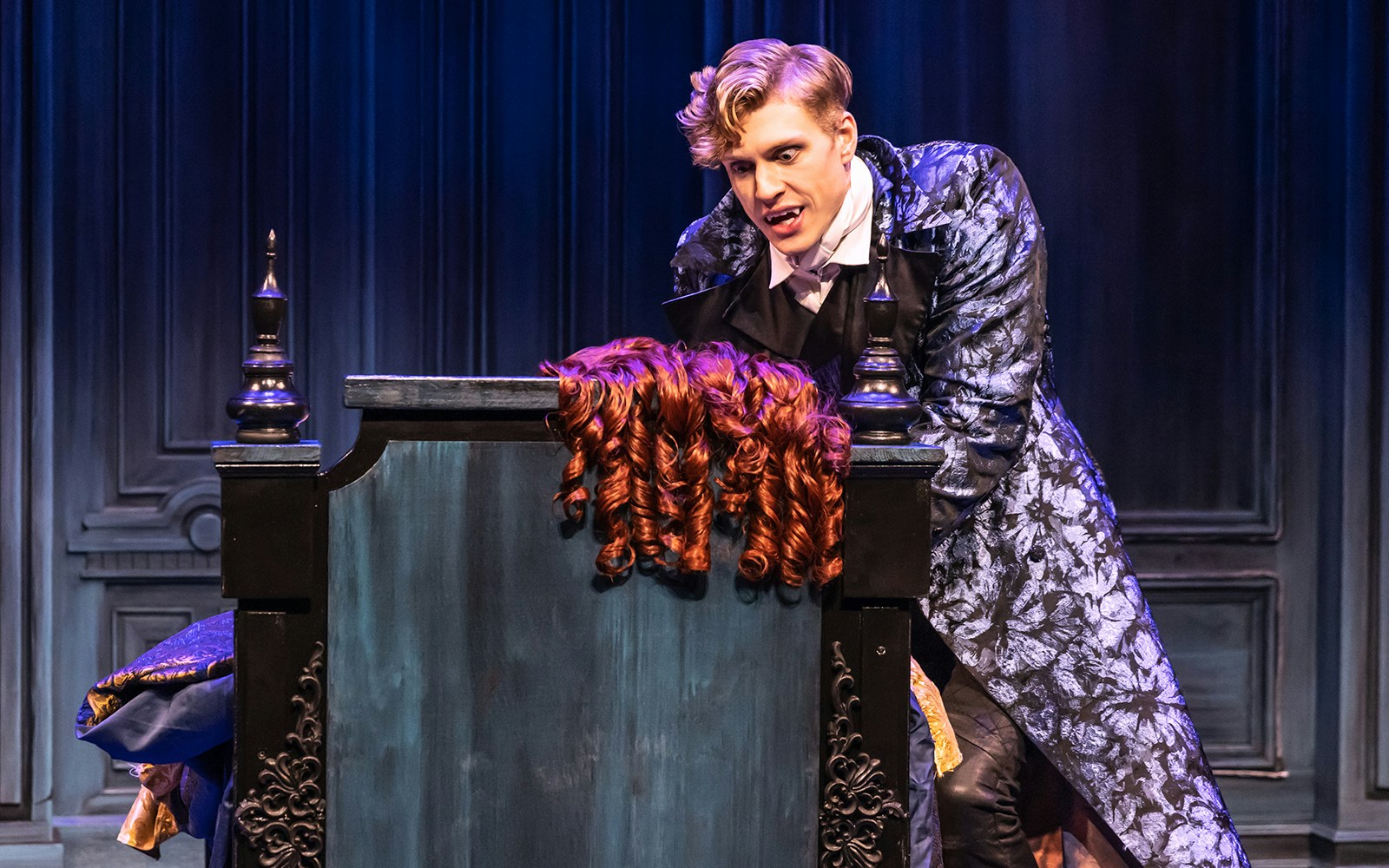 Actor in ornate costume leaning over a coffin in "Dracula, A Comedy of Terrors" stage scene.