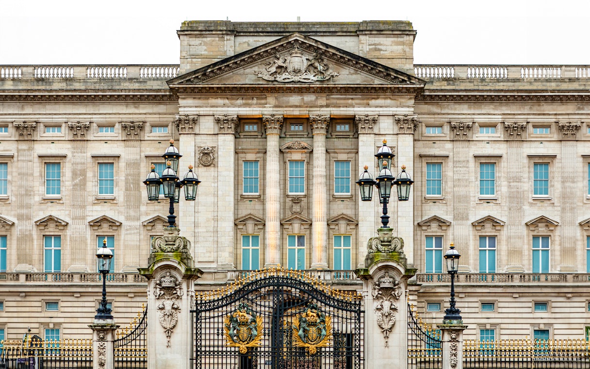 Buckingham Palace facade with ornate gates and lampposts, London.