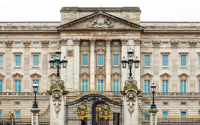 Buckingham Palace facade with ornate gates and lampposts, London.