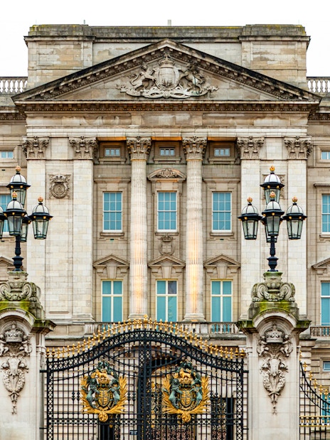 Buckingham Palace facade with ornate gates and lampposts, London.