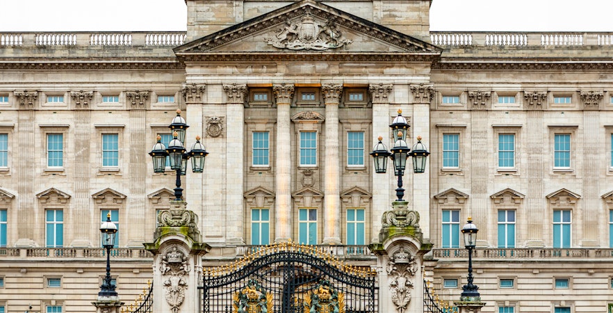 Buckingham Palace facade with ornate gates and lampposts, London.