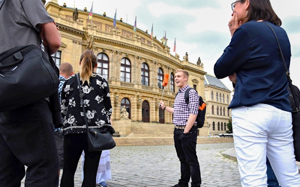 Tour group with guide outside Prague's historic Rudolfinum building.