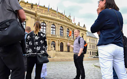 Tour group with guide outside Prague's historic Rudolfinum building.