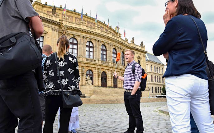 Tour group with guide outside Prague's historic Rudolfinum building.