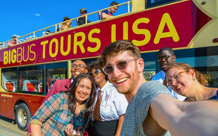 Group taking a selfie in front of a Big Bus Tours vehicle during Washington DC Hop-On-Hop-Off Tour.