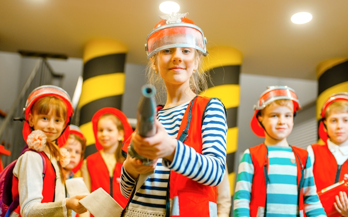 Children in firefighter costumes at KidsSTOP Singapore.