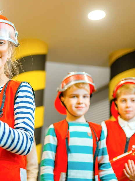 Children in firefighter costumes at KidsSTOP Singapore.