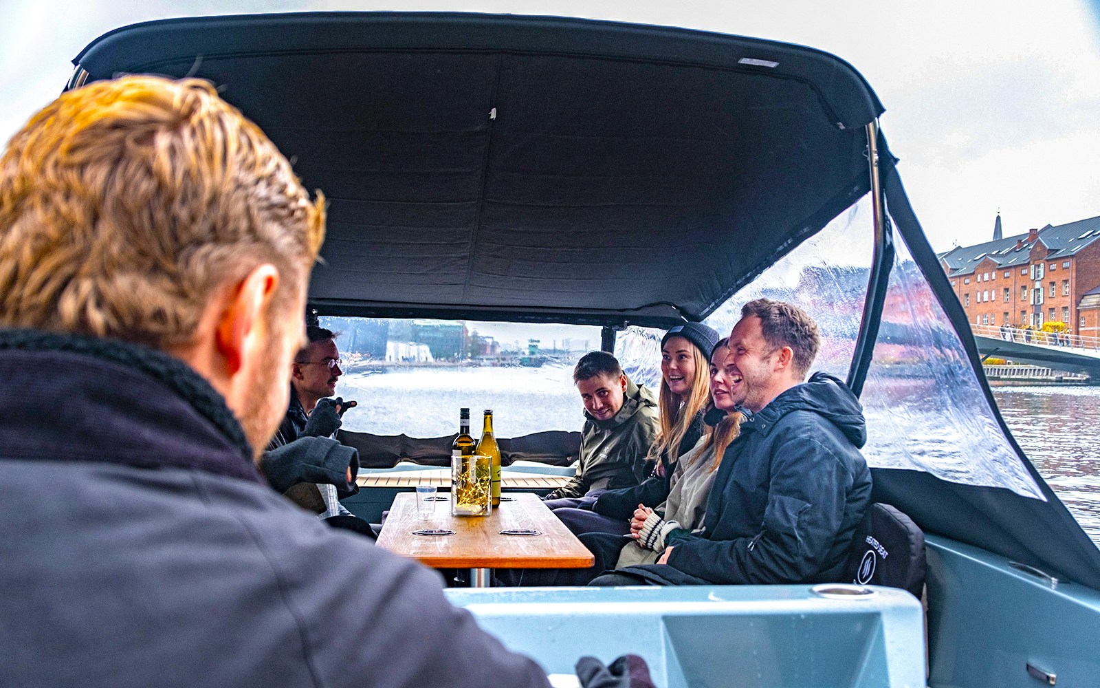 Guests on an electric boat enjoying a small group canal cruise in a city setting.