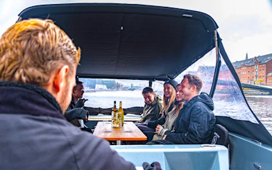 Guests on an electric boat enjoying a small group canal cruise in a city setting.