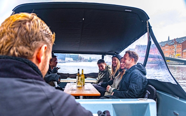 Guests on an electric boat enjoying a small group canal cruise in a city setting.