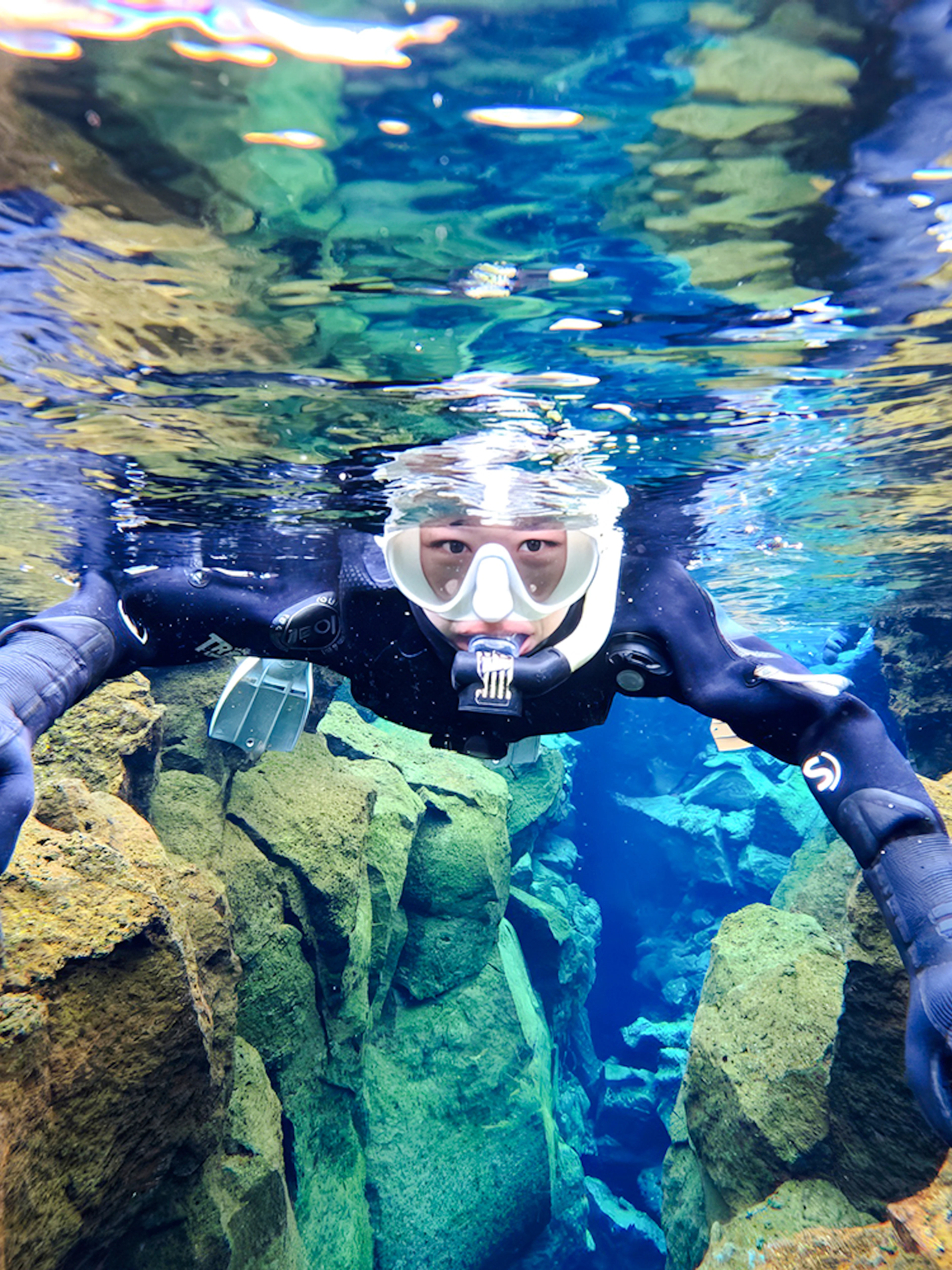 Snorkeler exploring Silfra's clear waters and rocky formations in Iceland.