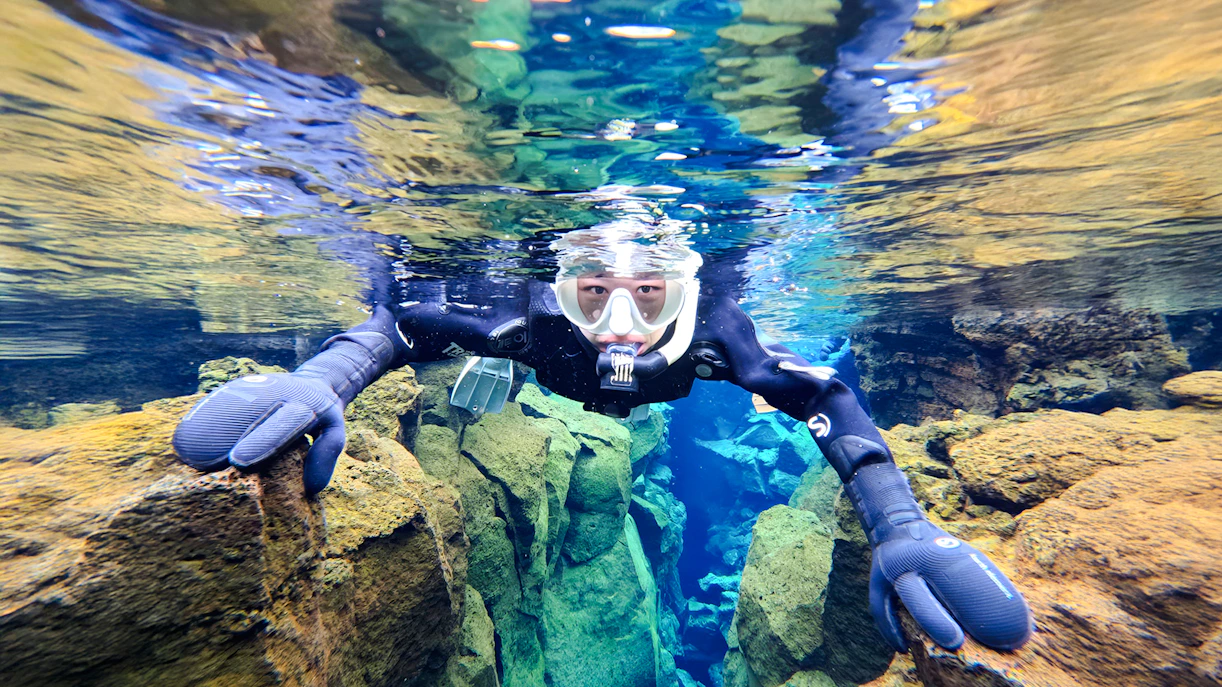 Snorkeler exploring Silfra's clear waters and rocky formations in Iceland.