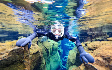 Snorkeler exploring Silfra's clear waters and rocky formations in Iceland.