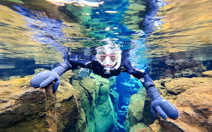 Snorkeler exploring Silfra's clear waters and rocky formations in Iceland.