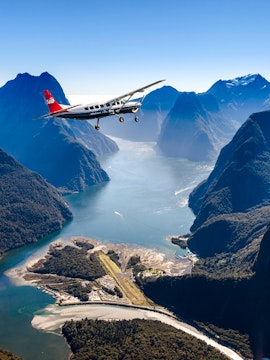 Aerial view of Milford Sound with cruise ship and plane, Queenstown scenic flyover experience.
