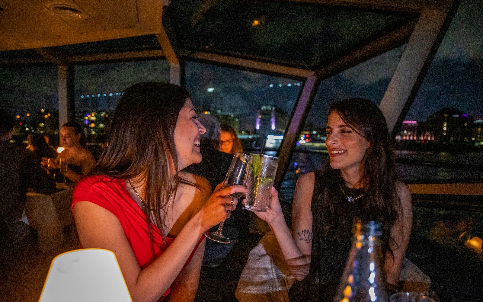 Guests enjoying evening drinks on the Thames River Cruise with London skyline in the background.