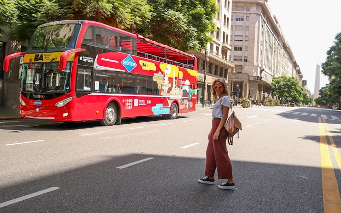 Woman crossing street near Buenos Aires hop-on hop-off bus.