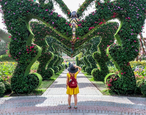 Visitor exploring floral archway at Dubai Miracle Garden.