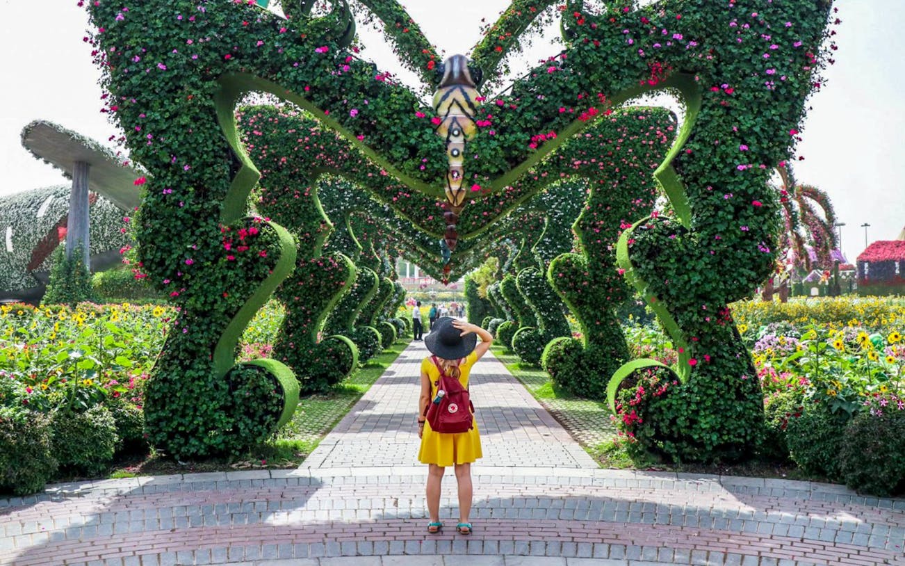 Visitor exploring floral archway at Dubai Miracle Garden.
