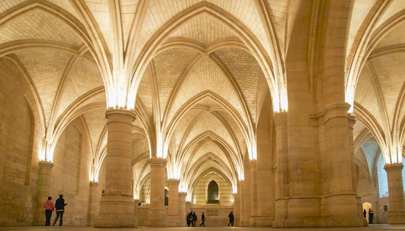 Visitors exploring the vaulted halls of the Conciergerie in Paris.