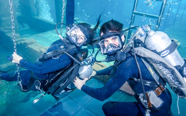 Divers exploring underwater ruins during Sunken City Walk tour.